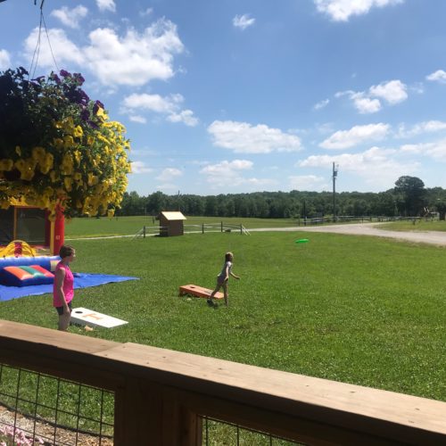 Mother and child play corn hole and toss frisbee in a field