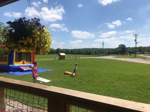 Mother and child play corn hole and toss frisbee in a field