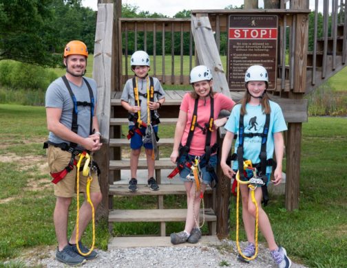 family smiling at the zipline station
