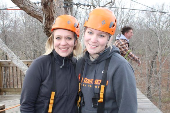 mother and daughter smiling outside at a zipline event